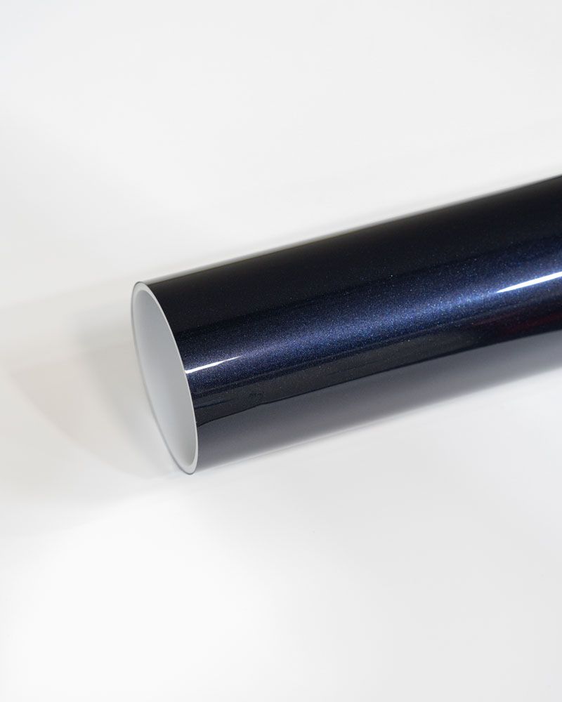 A close up of a blue metallic vinyl wrap on a white surface.