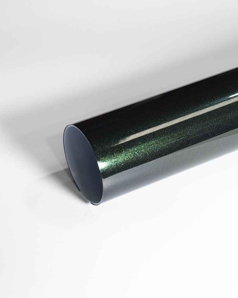 A close up of a green metal pipe on a white surface.