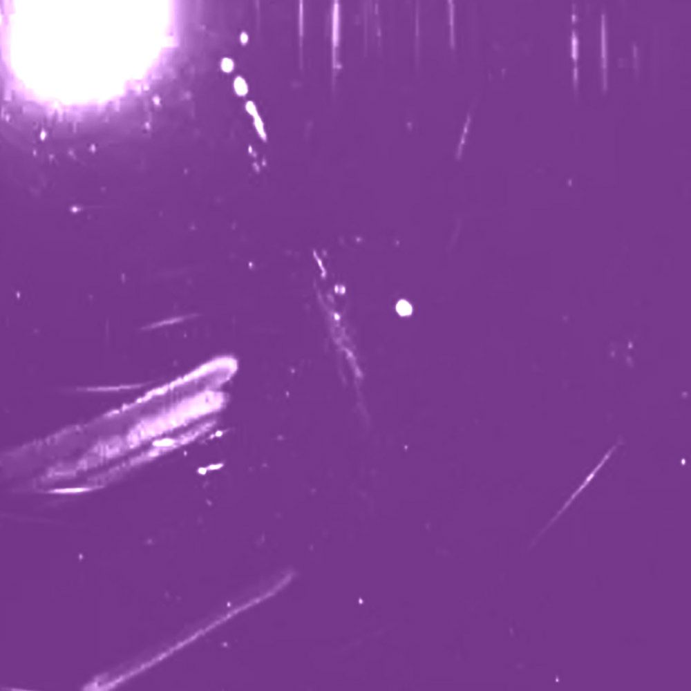 Purple-tinted night sky with a bright light source in the upper left and streaks of light across the image.