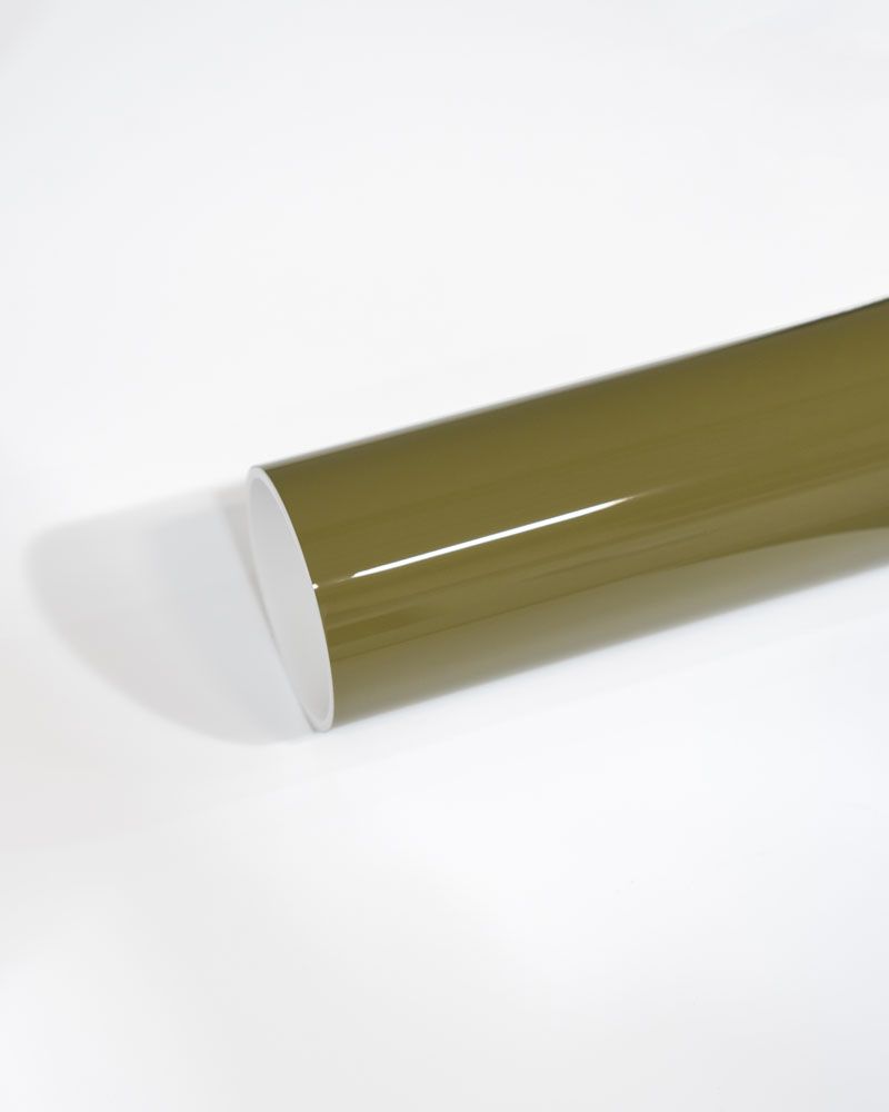 A close up of a green plastic tube on a white surface.
