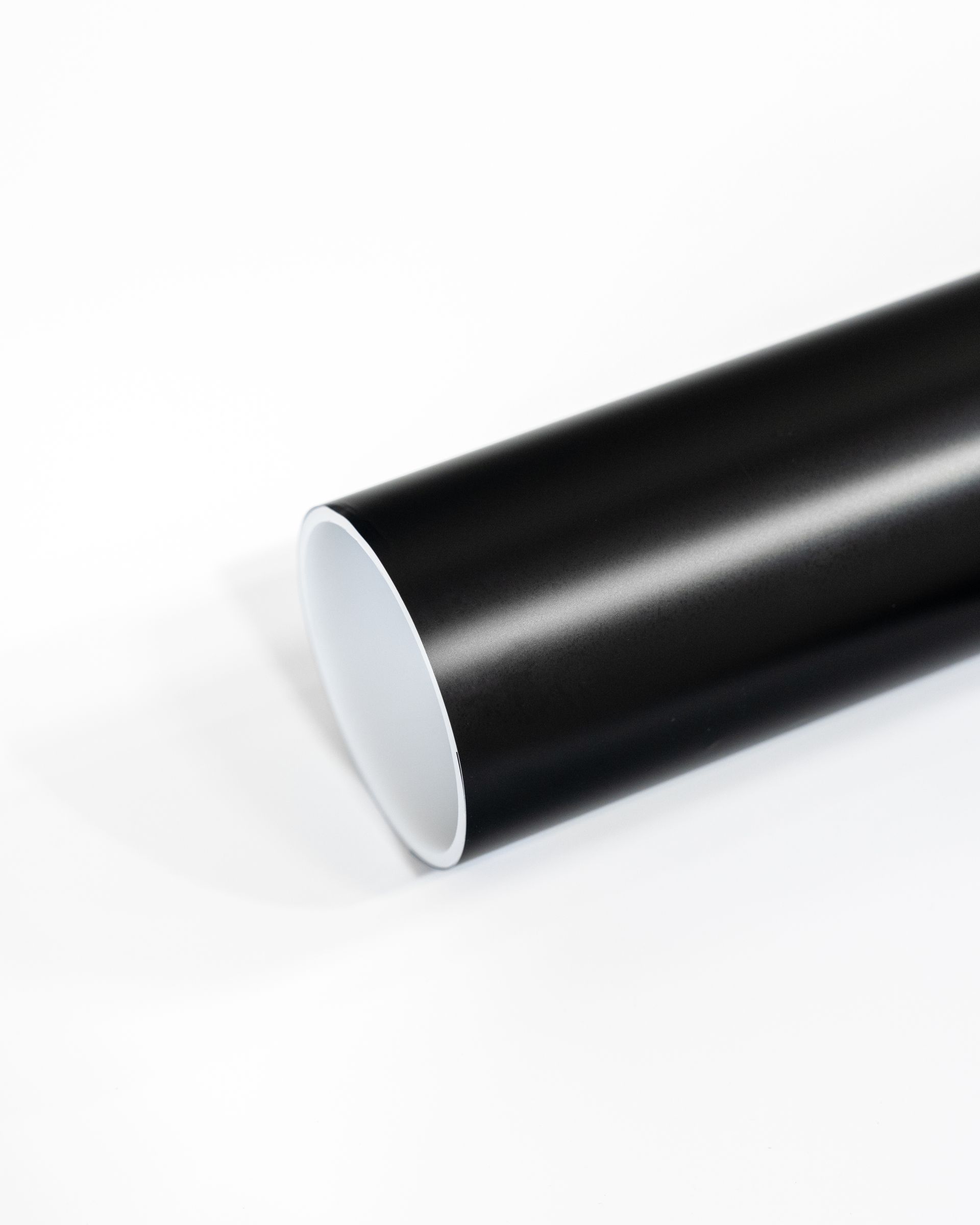 A close up of a black pipe on a white surface.