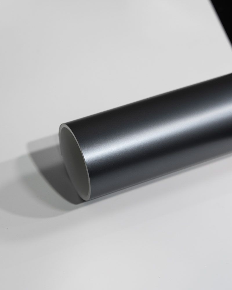 A close up of a black metal pipe on a white surface.