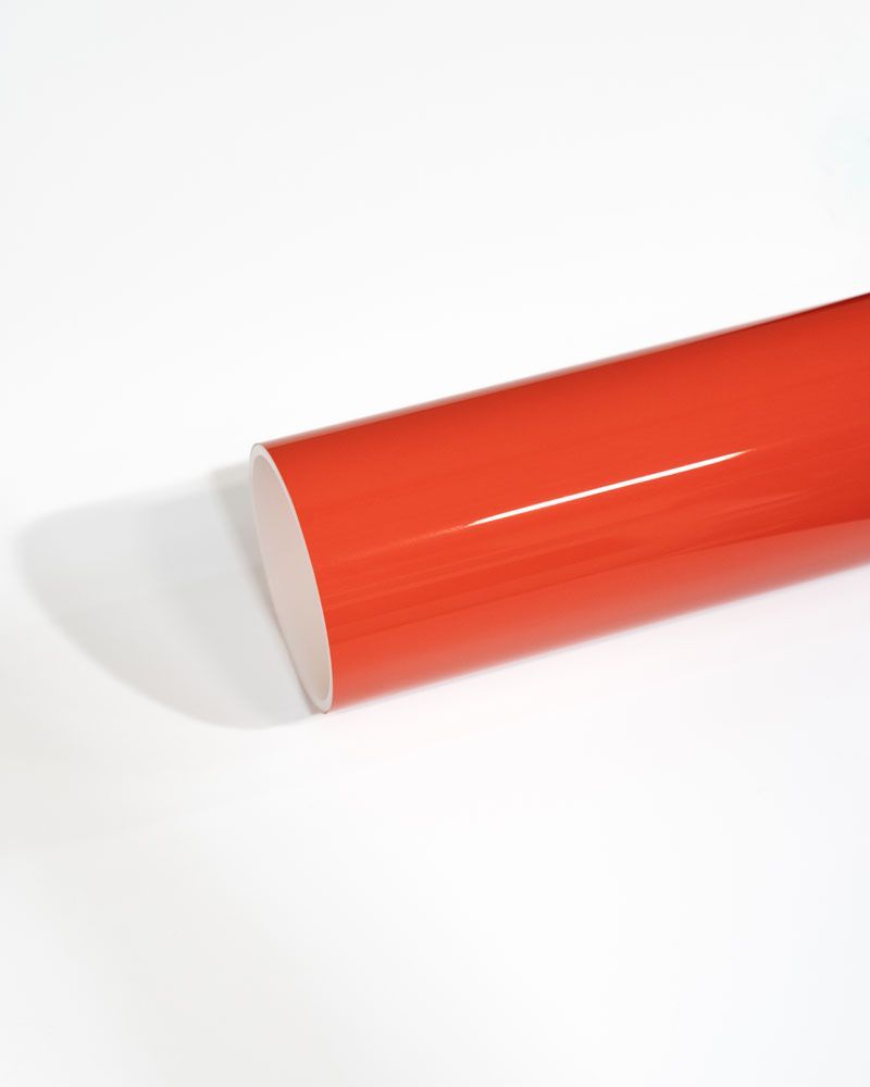 A close up of a red tube on a white surface.