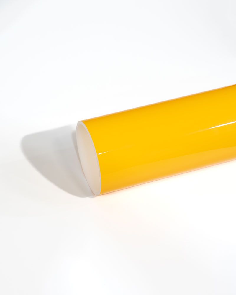 A close up of a yellow plastic tube on a white surface.