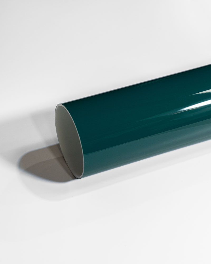 A green pipe is sitting on a white surface.