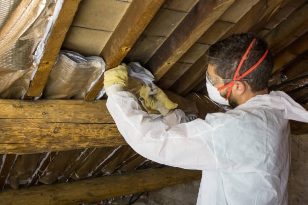 A man wearing a mask and gloves is working on a wooden ceiling.