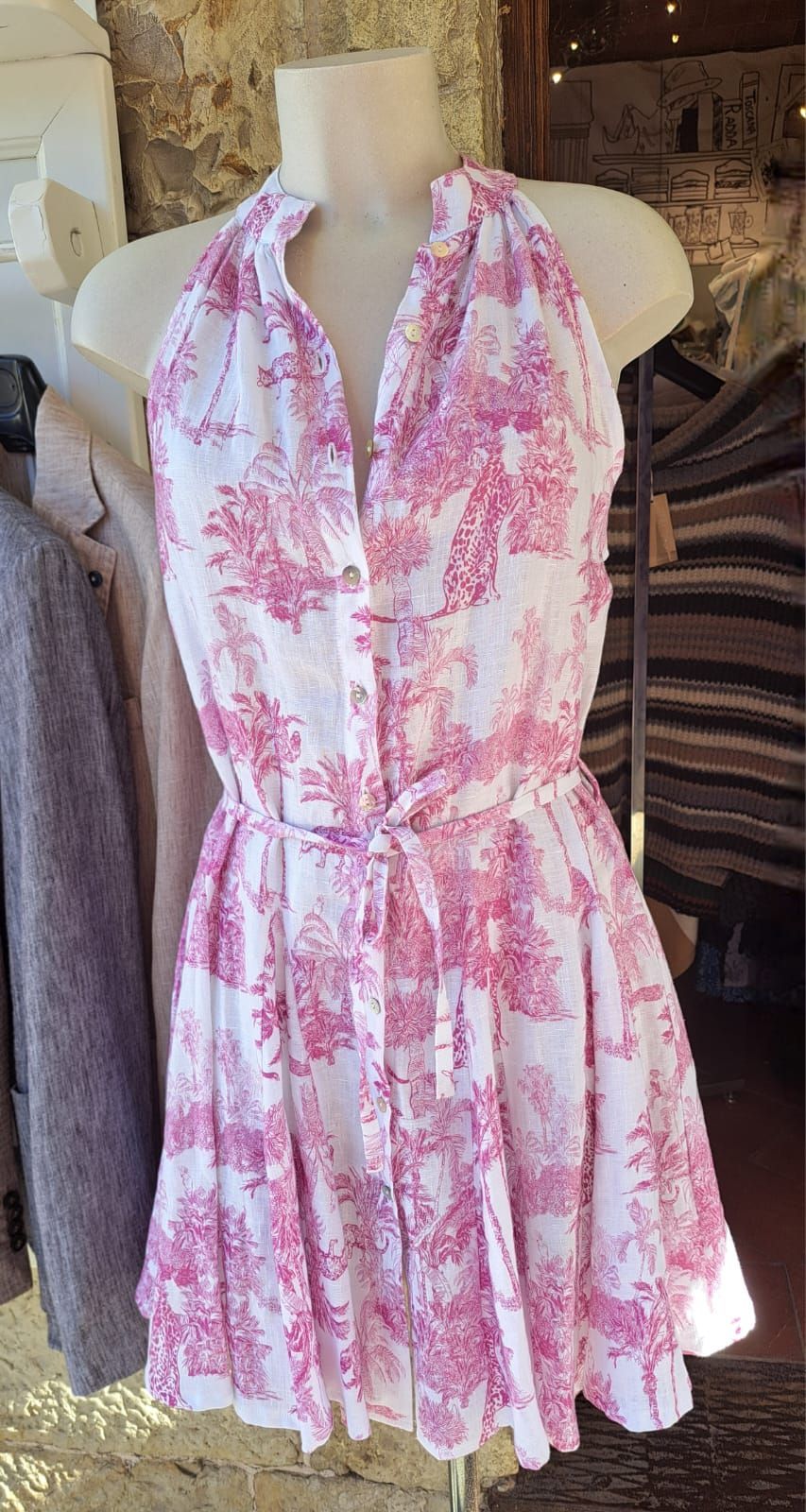 Abito a collo alto con stampa floreale rosa e bianca e cintura in vita, indossato da un manichino.