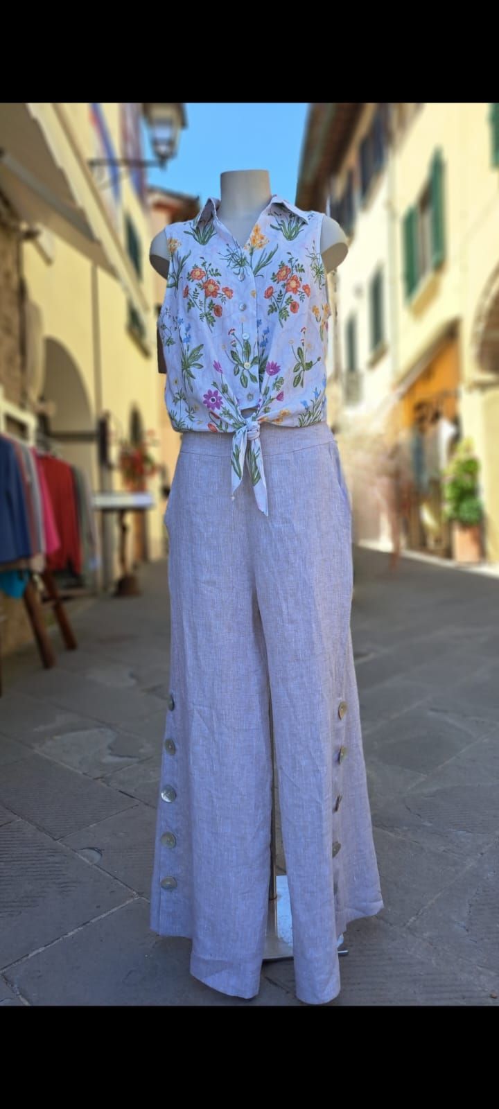 Top senza maniche a fantasia floreale con pantaloni a gamba larga a vita alta color lavanda, esposti su un manichino all'aperto.