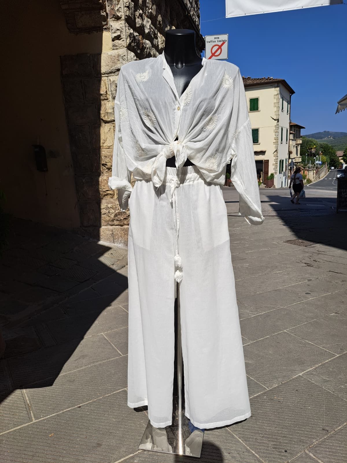 Completo bianco a maniche lunghe esposto su un manichino all'aperto, in una strada soleggiata.