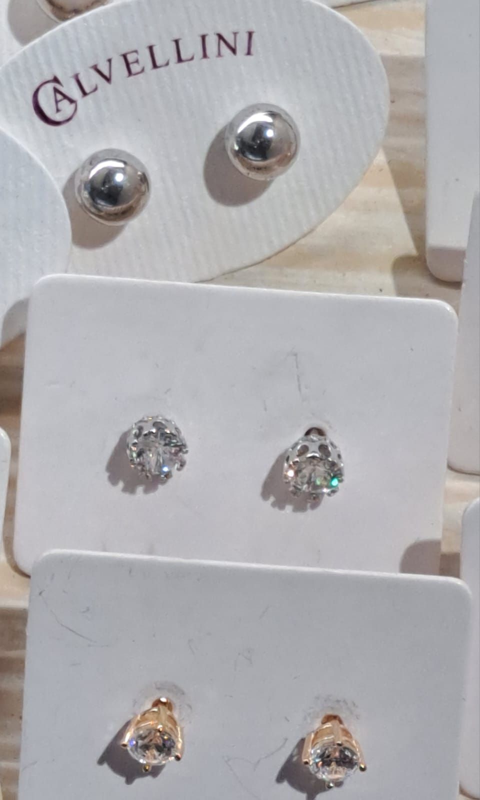 Esposizione di orecchini a perno in argento e bianco su cartoncini di marca.