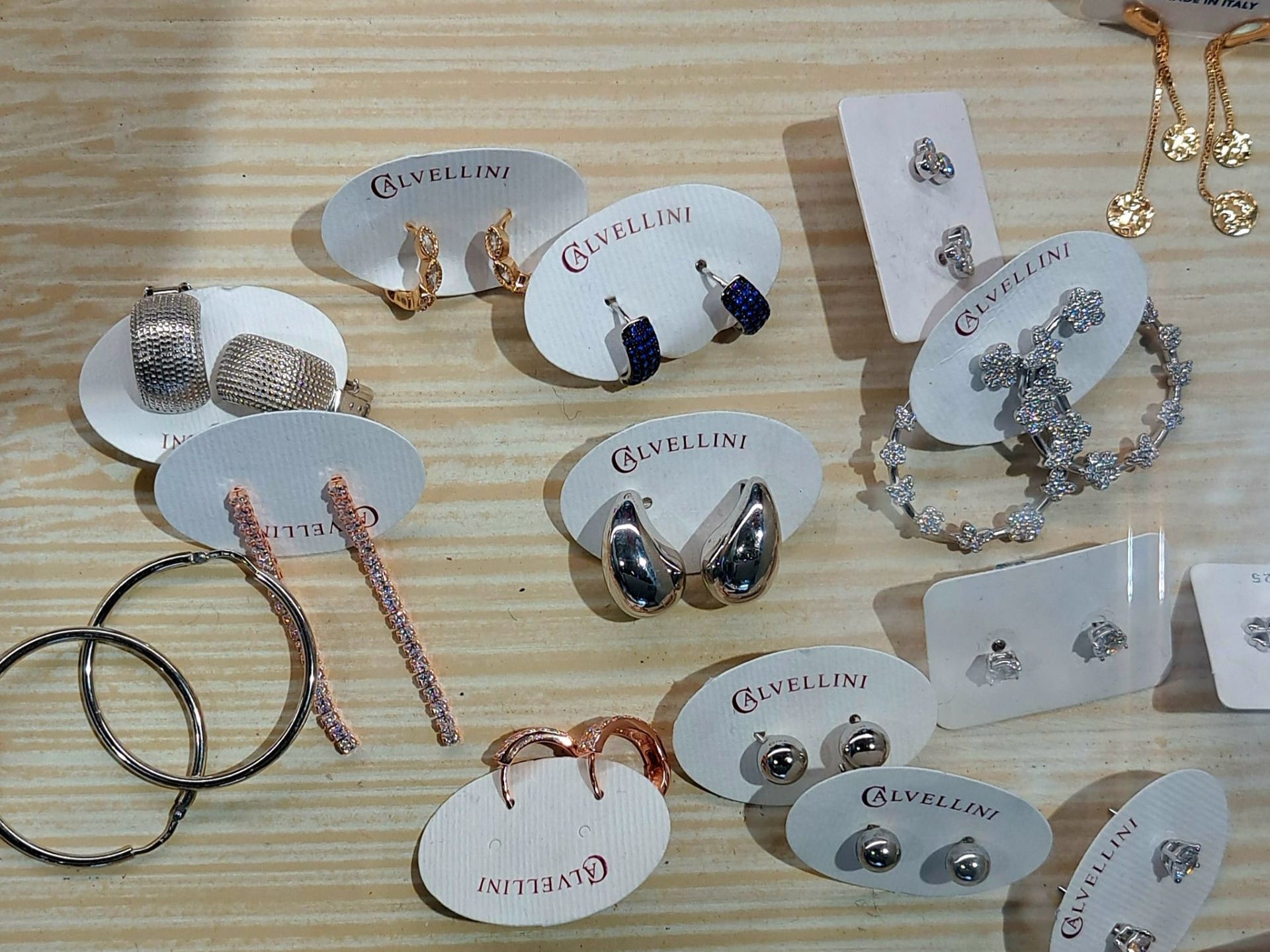 Assortimento di orecchini fatti a mano su cartoncini, disposti su una superficie di legno chiaro.