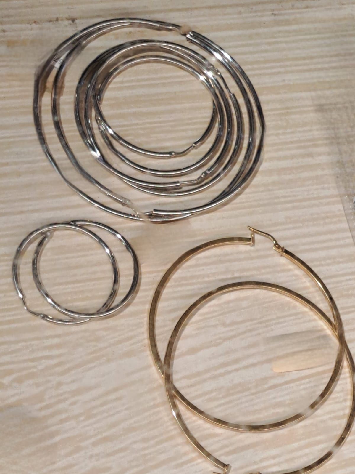 Tre anelli di filo metallico sovrapposti su una superficie di legno chiaro, con due anelli più piccoli sottostanti.
