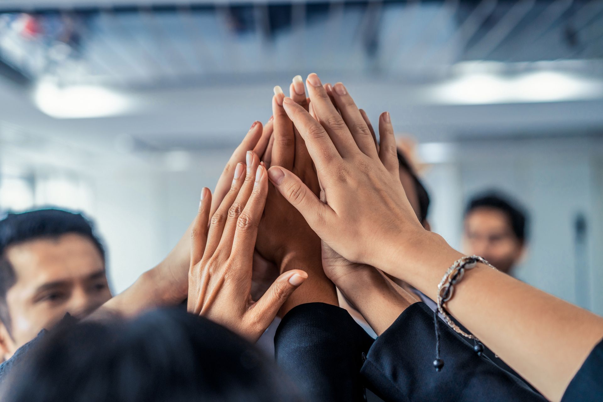 A group of people place their hands together in the center in a gesture of unity and teamwork.