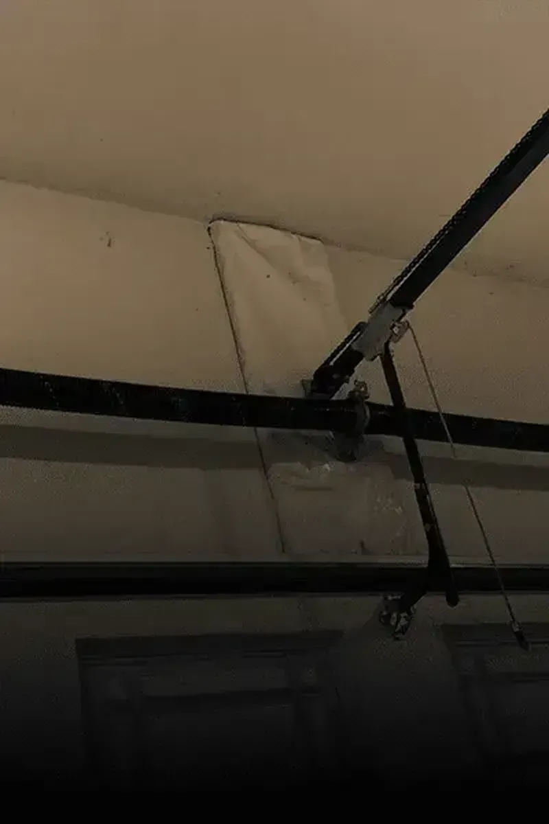 A garage door opener rail attached to a wall, with a white protective cover over the mounting bracket.