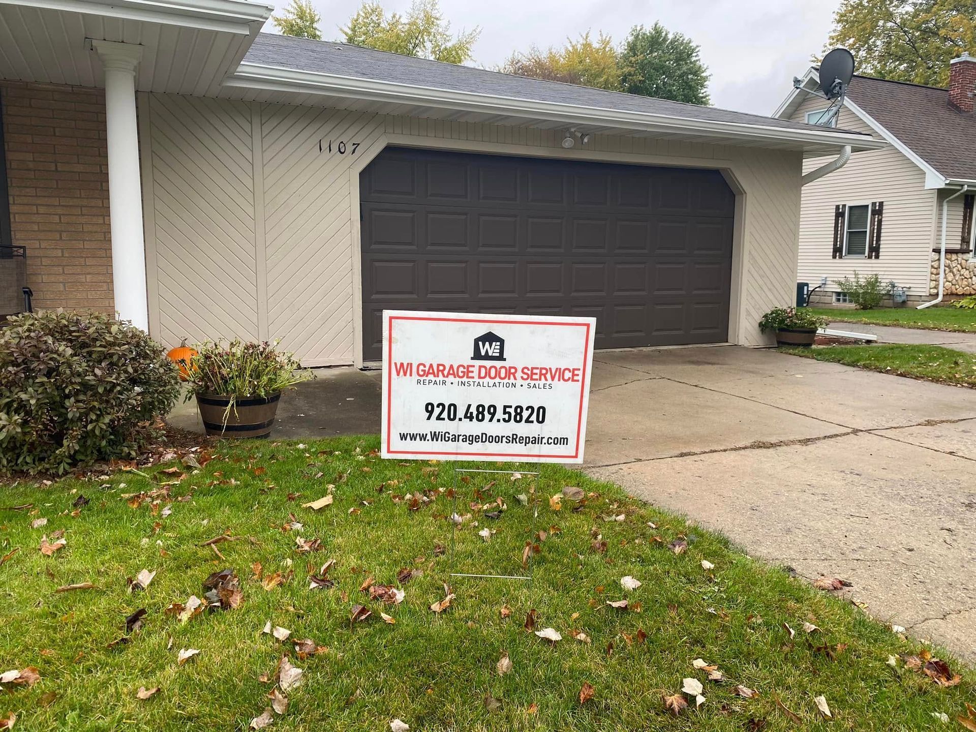 Suburban house with a garage and a yard sign for roofing services in the front lawn