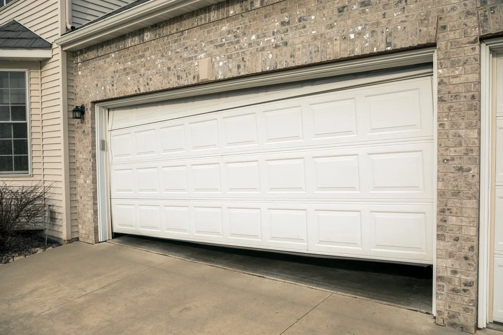 Closed white garage door on a suburban brick house driveway
