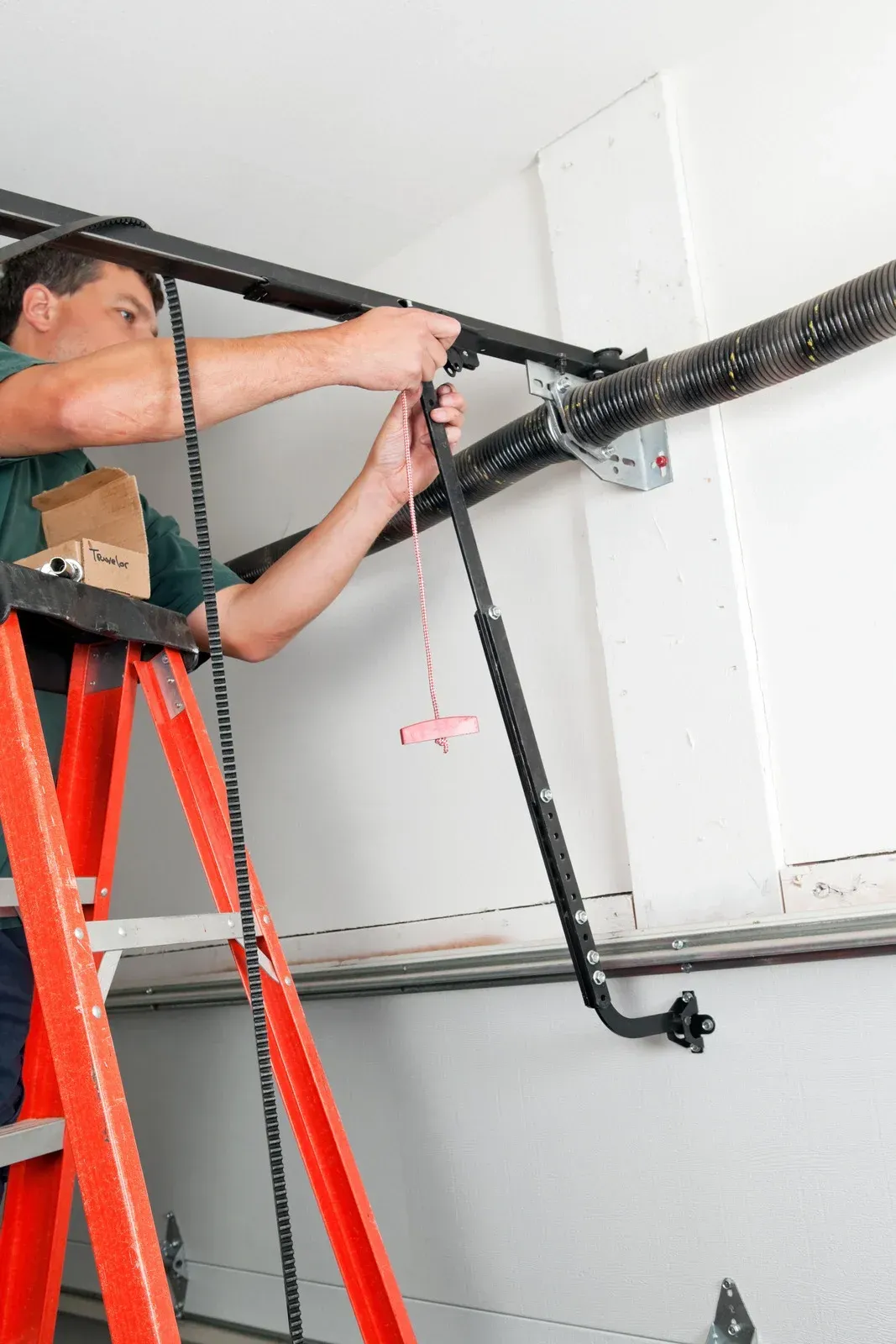 Worker on red ladder installing black overhead piping in a white room