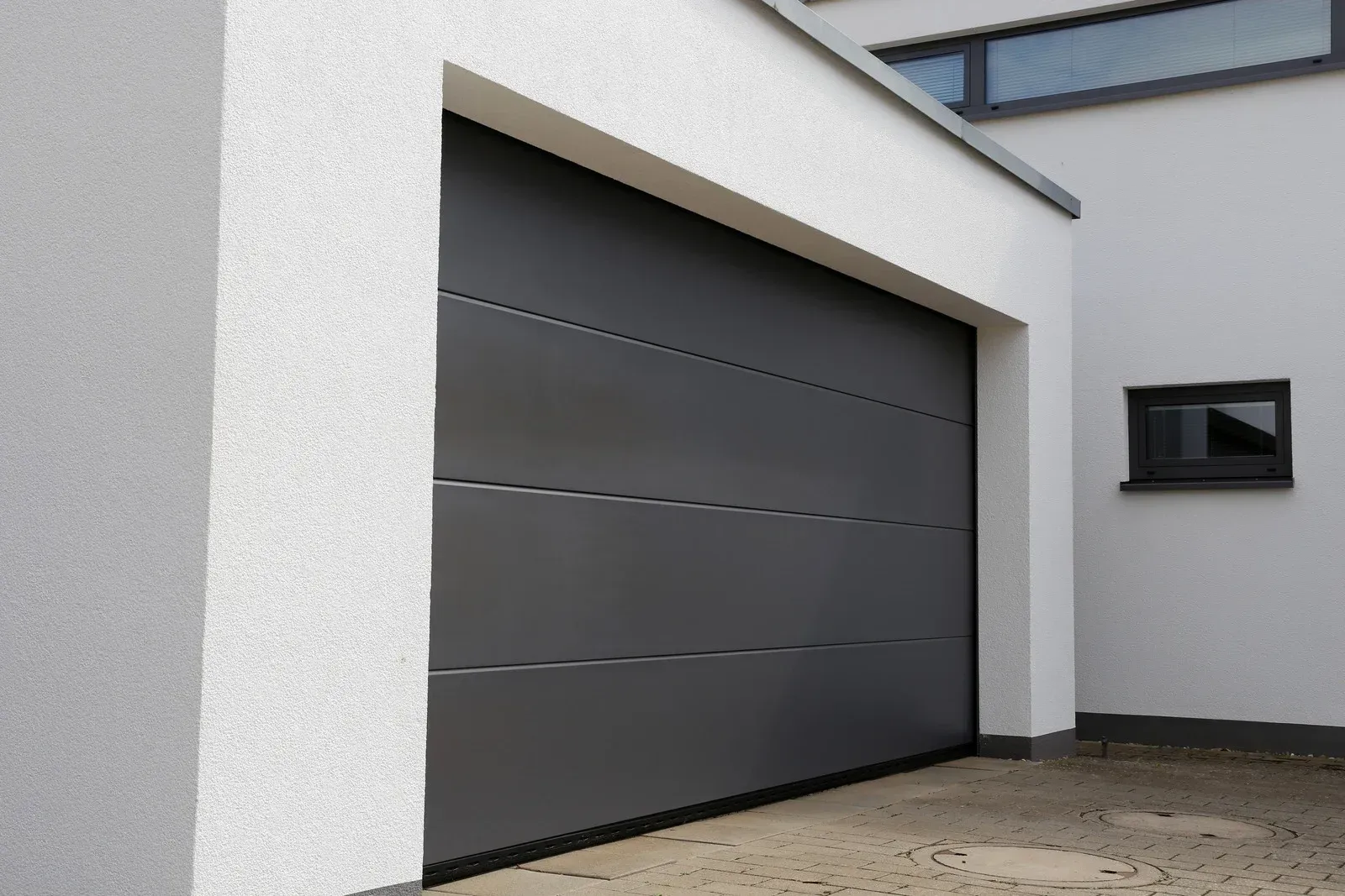 Modern gray garage door on a white house exterior