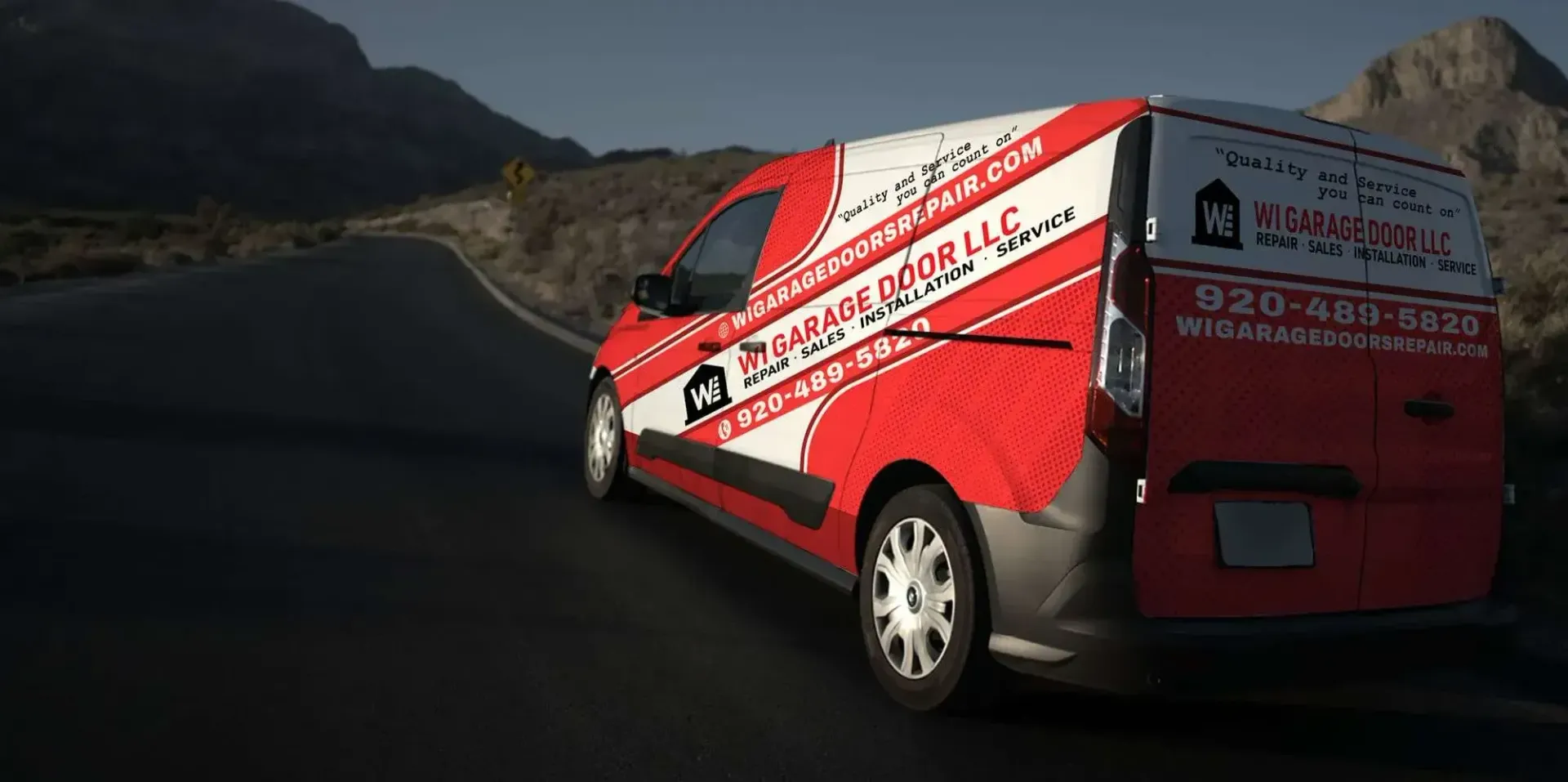 Red emergency response van on a winding mountain road, with white diagonal stripes and open rear door.