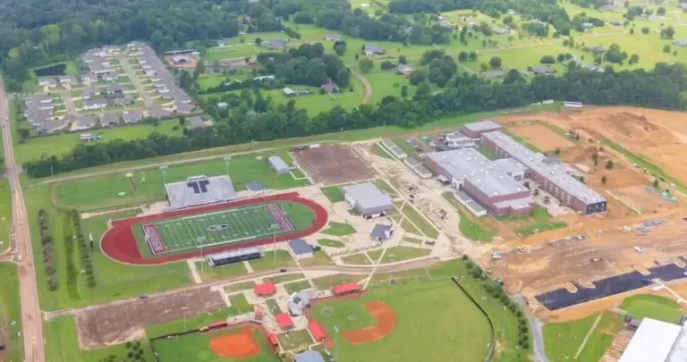 Aerial view of a high school campus with a football field, track, baseball field, and school buildings.