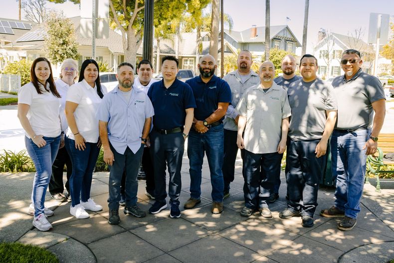 A group of people standing next to each other on a sidewalk.