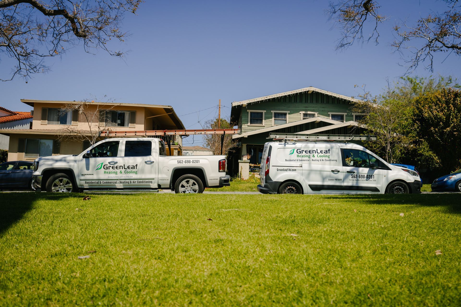 Two trucks and a van are parked in front of a house.