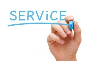 A hand is writing the word service with a blue marker.
