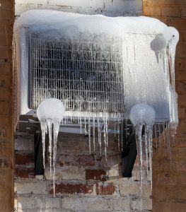 An air conditioner is covered in ice and snow