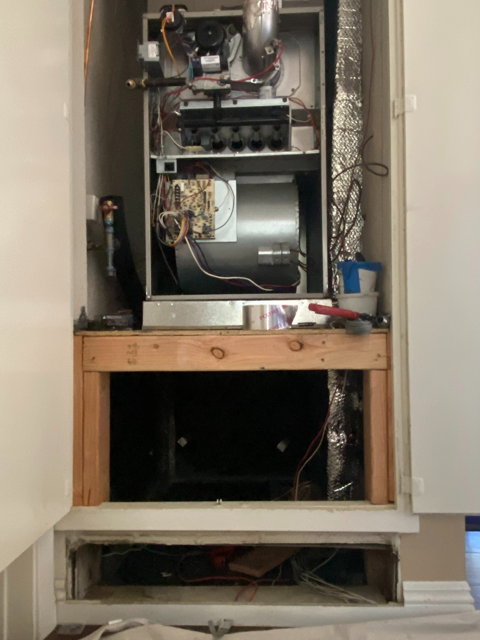 A stove is sitting inside of a cabinet with the door open.