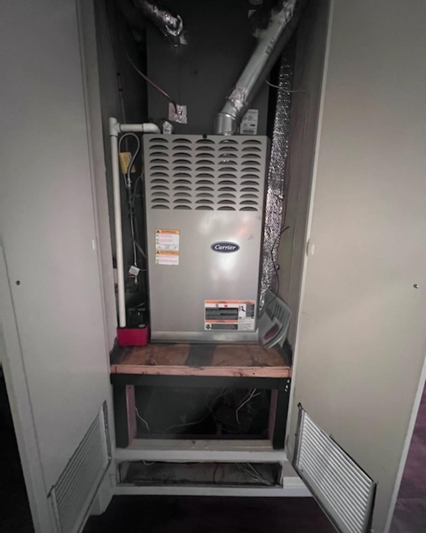 A furnace is sitting inside of a closet in a room.