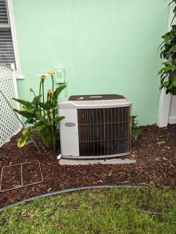 An air conditioner is sitting outside of a green house