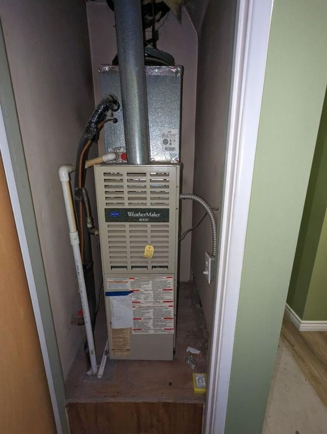 An air conditioner is sitting in a closet next to a door.