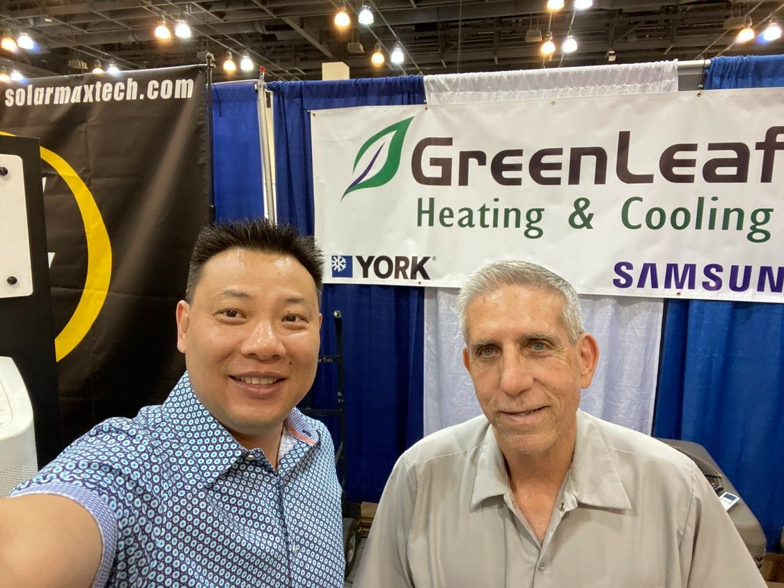Two men are posing for a picture in front of a greenleaf heating and cooling sign.
