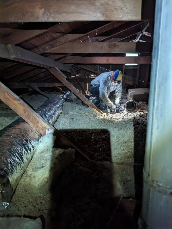 A man is working in the attic of a house.