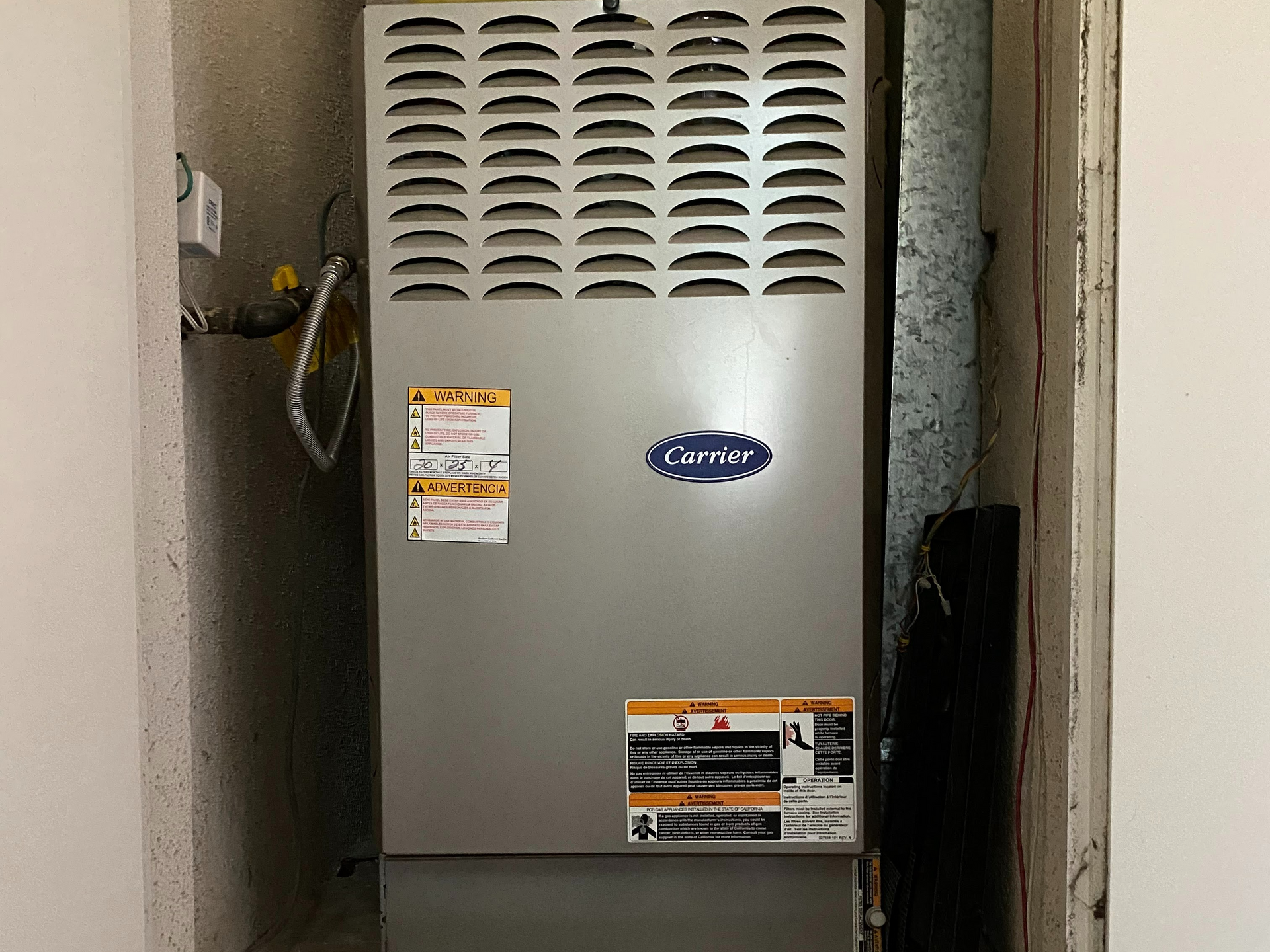 A carrier air conditioner is sitting in a corner of a room.