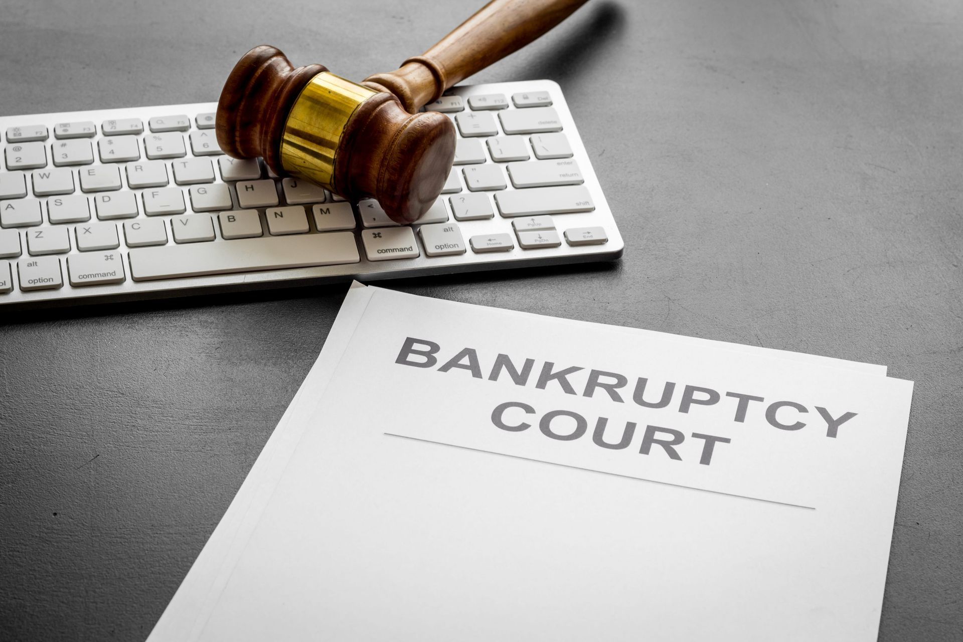 Gavel on keyboard beside paper labeled “BANKRUPTCY COURT”