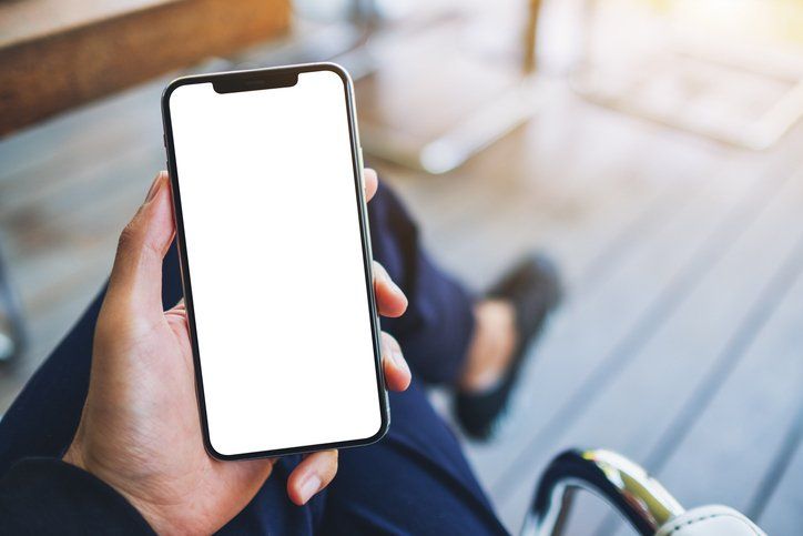 A man holding black mobile phone with blank white screen