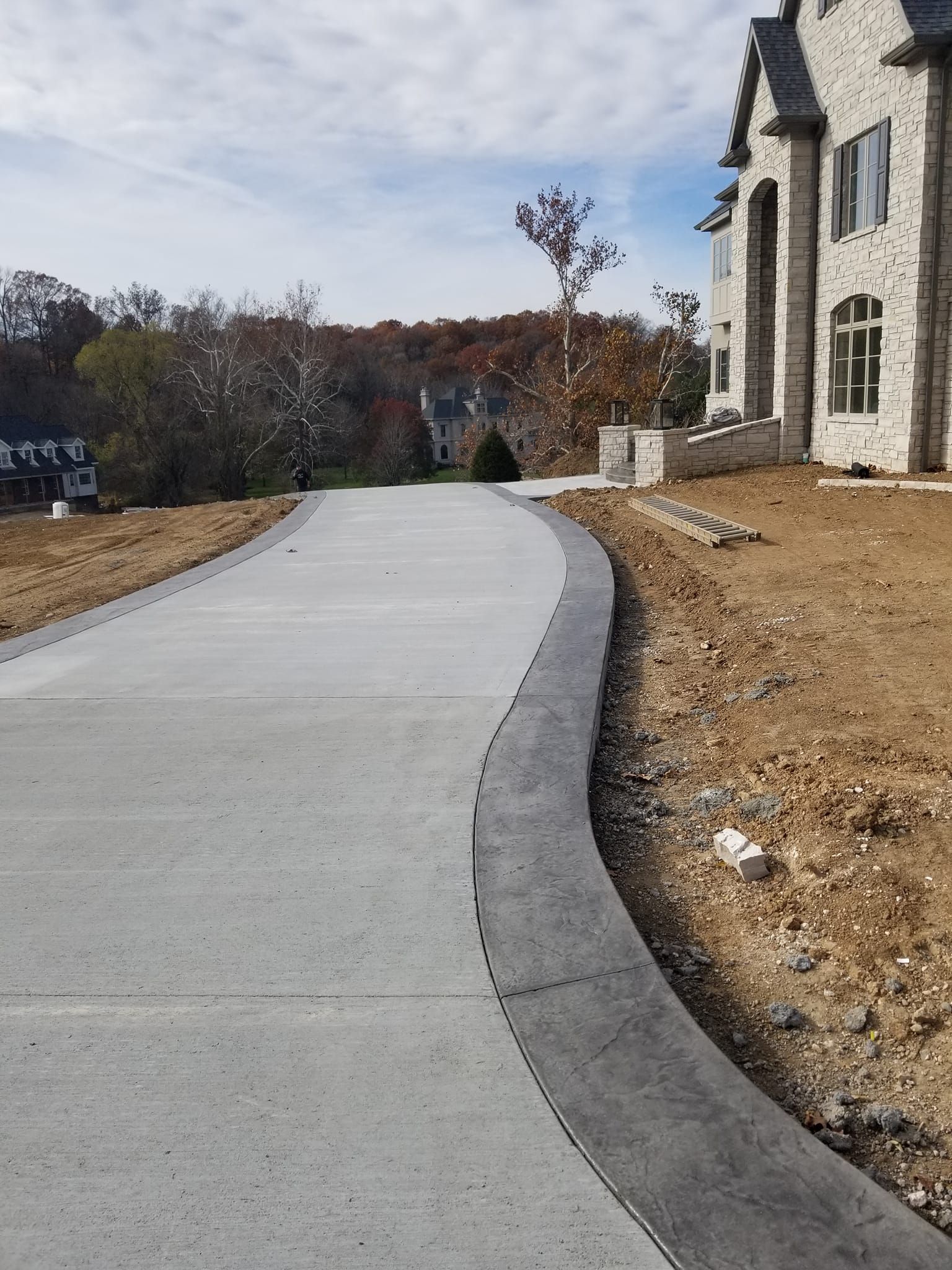 Concrete driveway curves toward a multi-story brick building. The driveway's edge is a darker color.