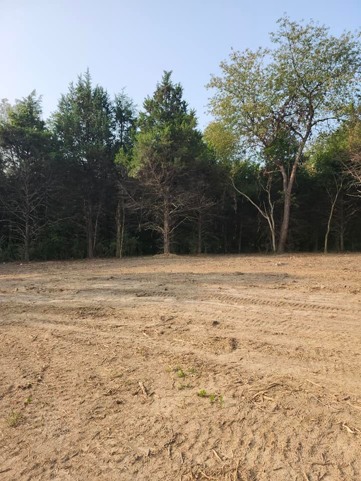 A cleared dirt lot with tire tracks in the foreground.