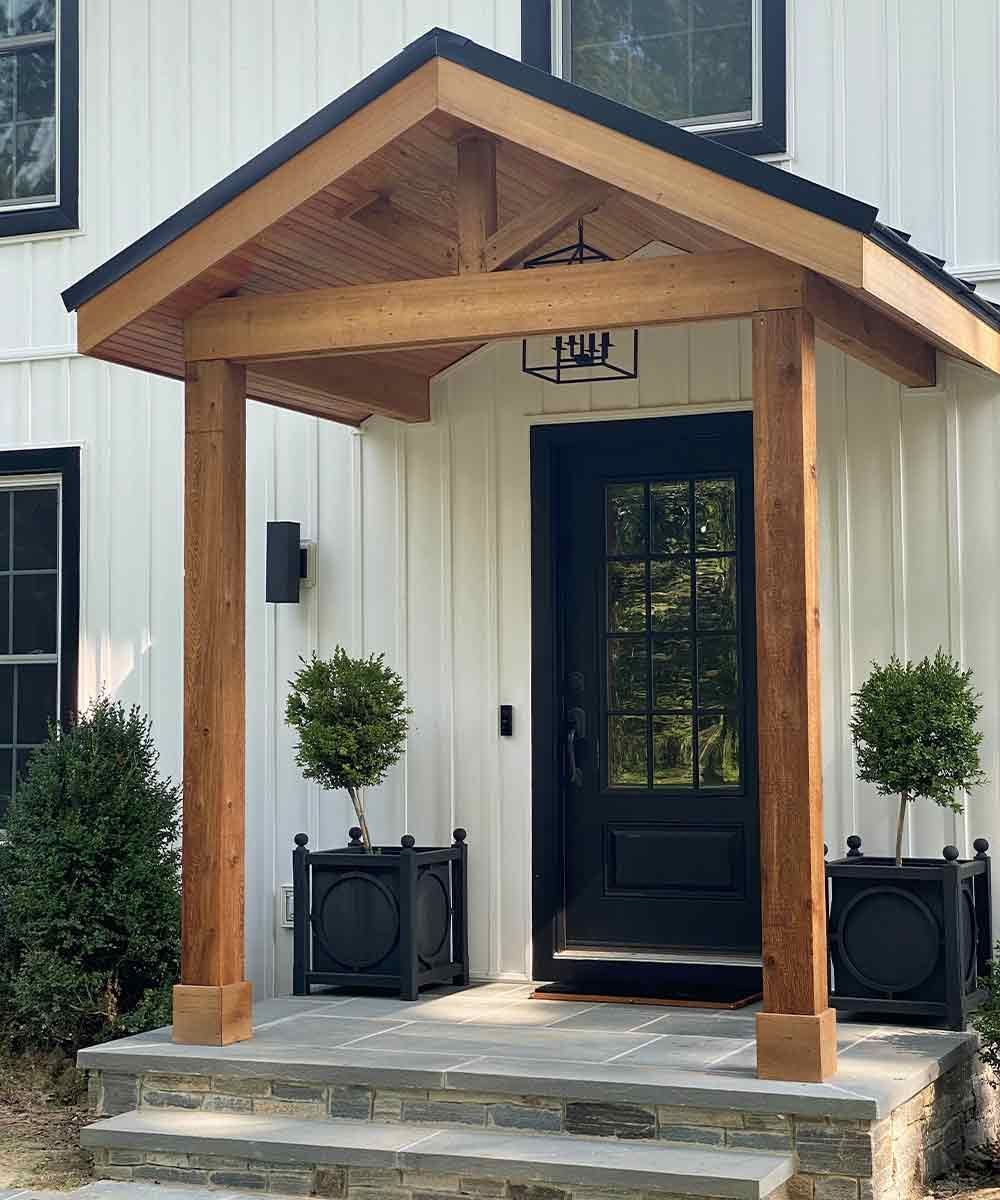 A white house with a black door and a wooden porch.