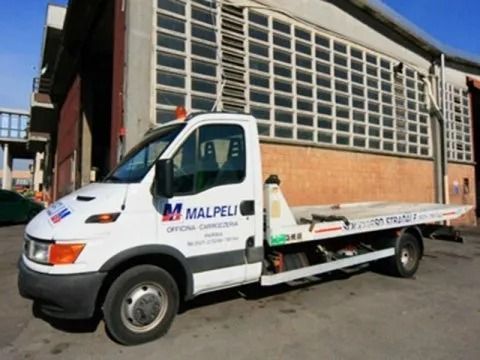 Un camioncino bianco con pianale e la scritta