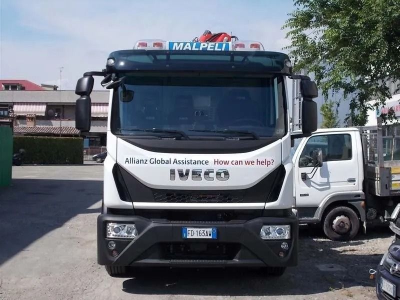 Vista frontale di un carro attrezzi Iveco bianco con il logo Allianz parcheggiato all'aperto.