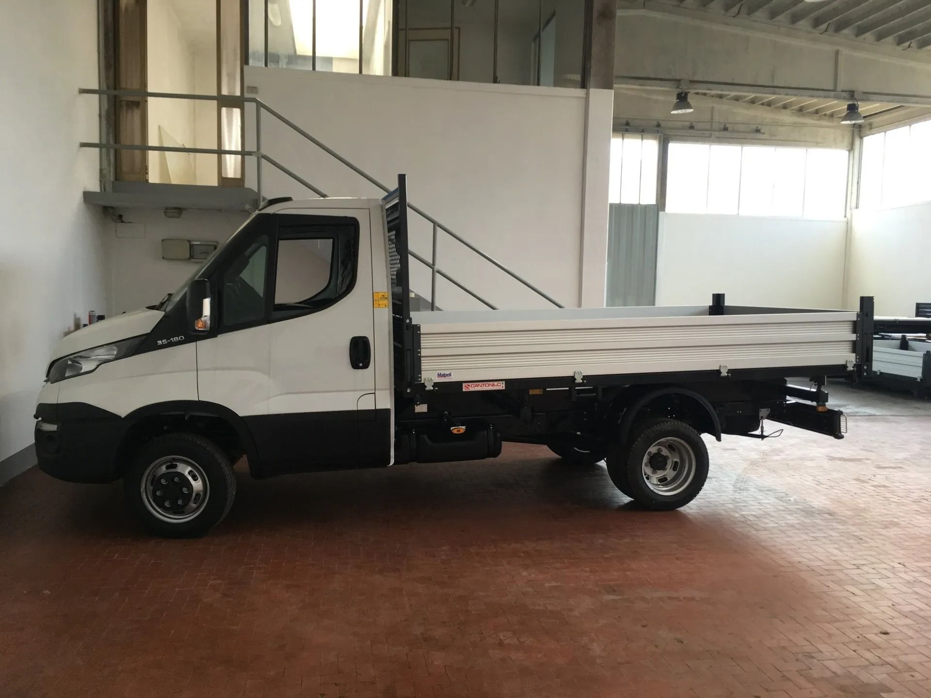 Camion a pianale bianco parcheggiato all'interno di un magazzino.