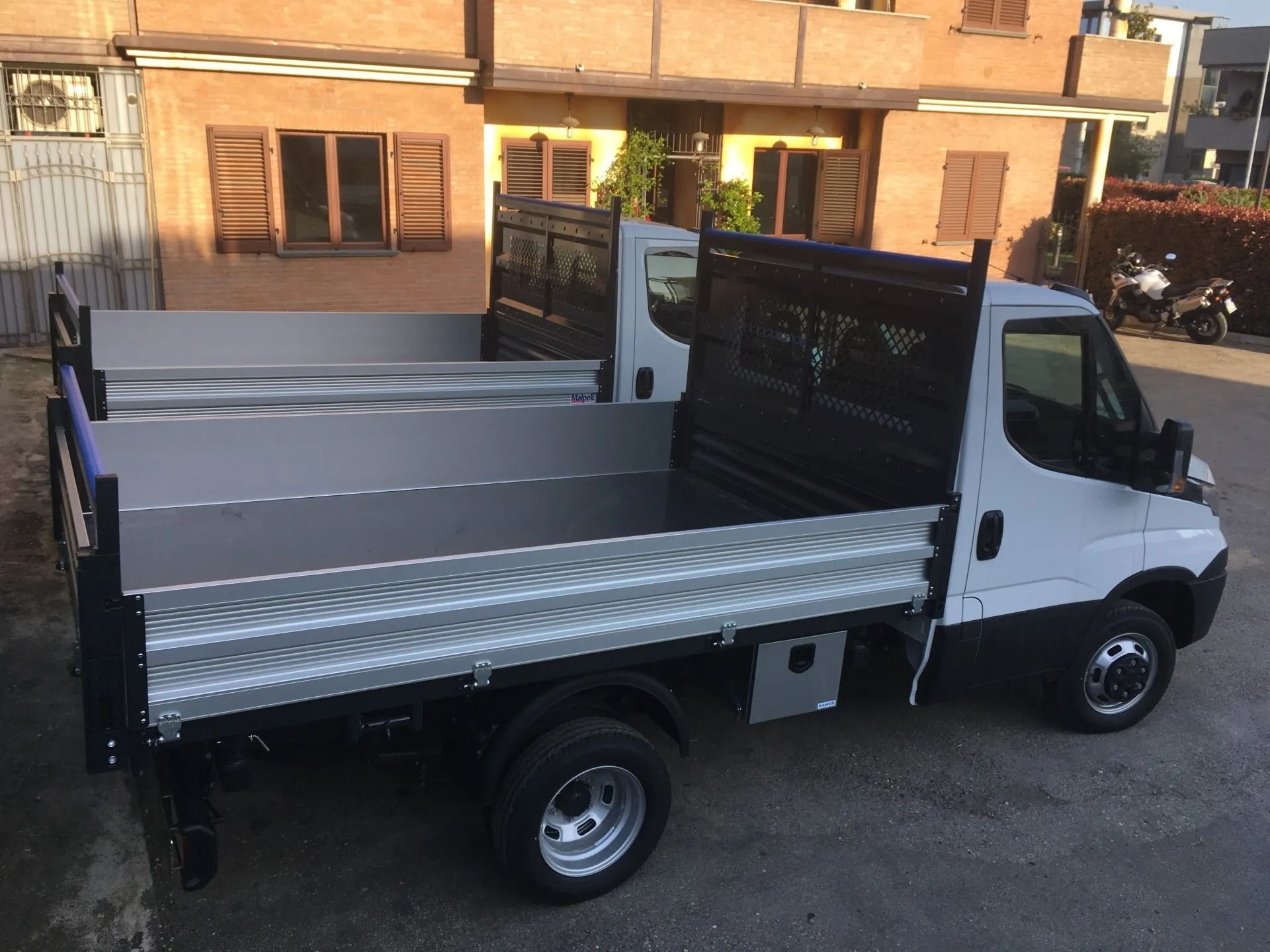Pick-up bianco con pianale ribassato parcheggiato fuori da un edificio, vista laterale