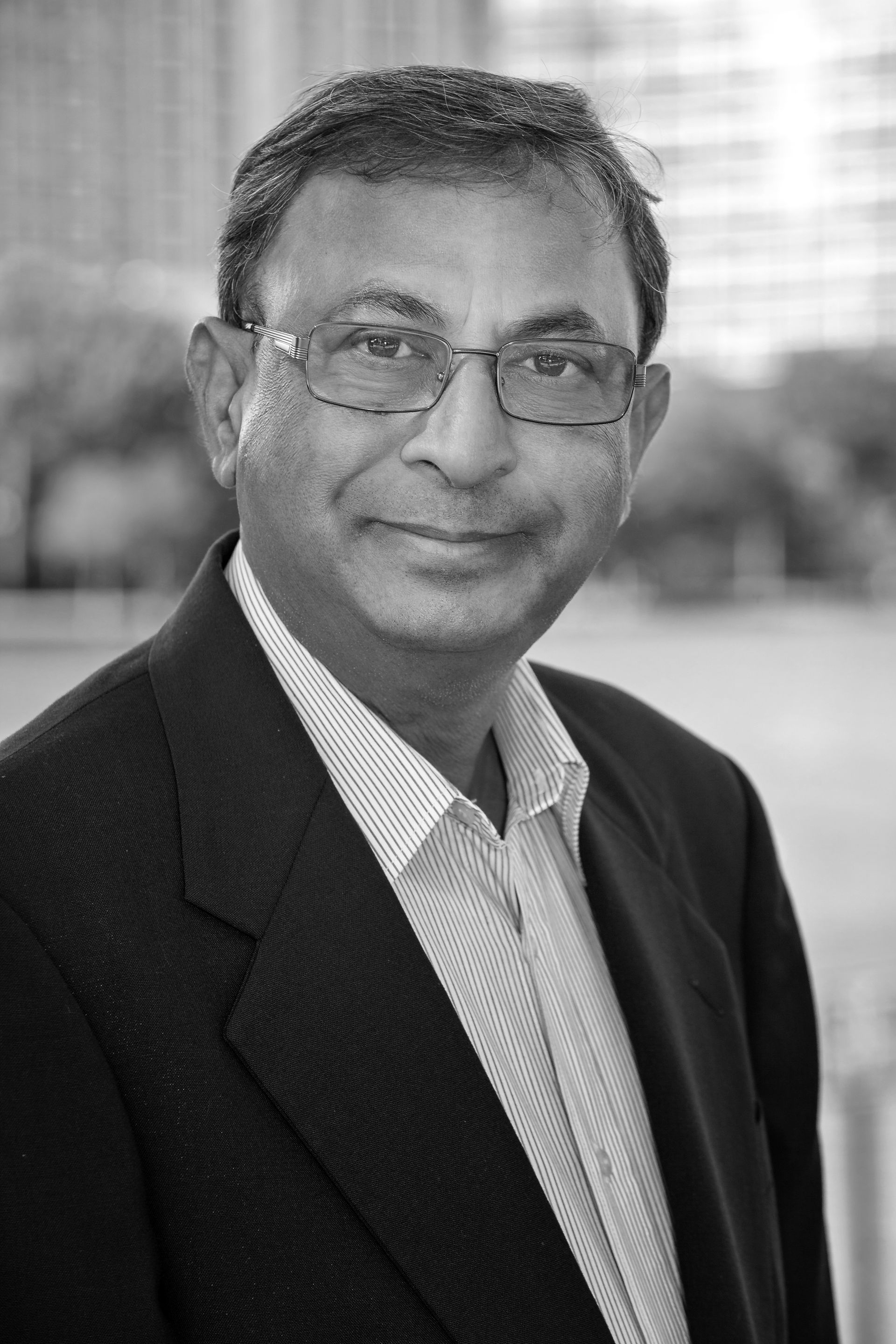 A black and white photo of a man wearing glasses and a suit