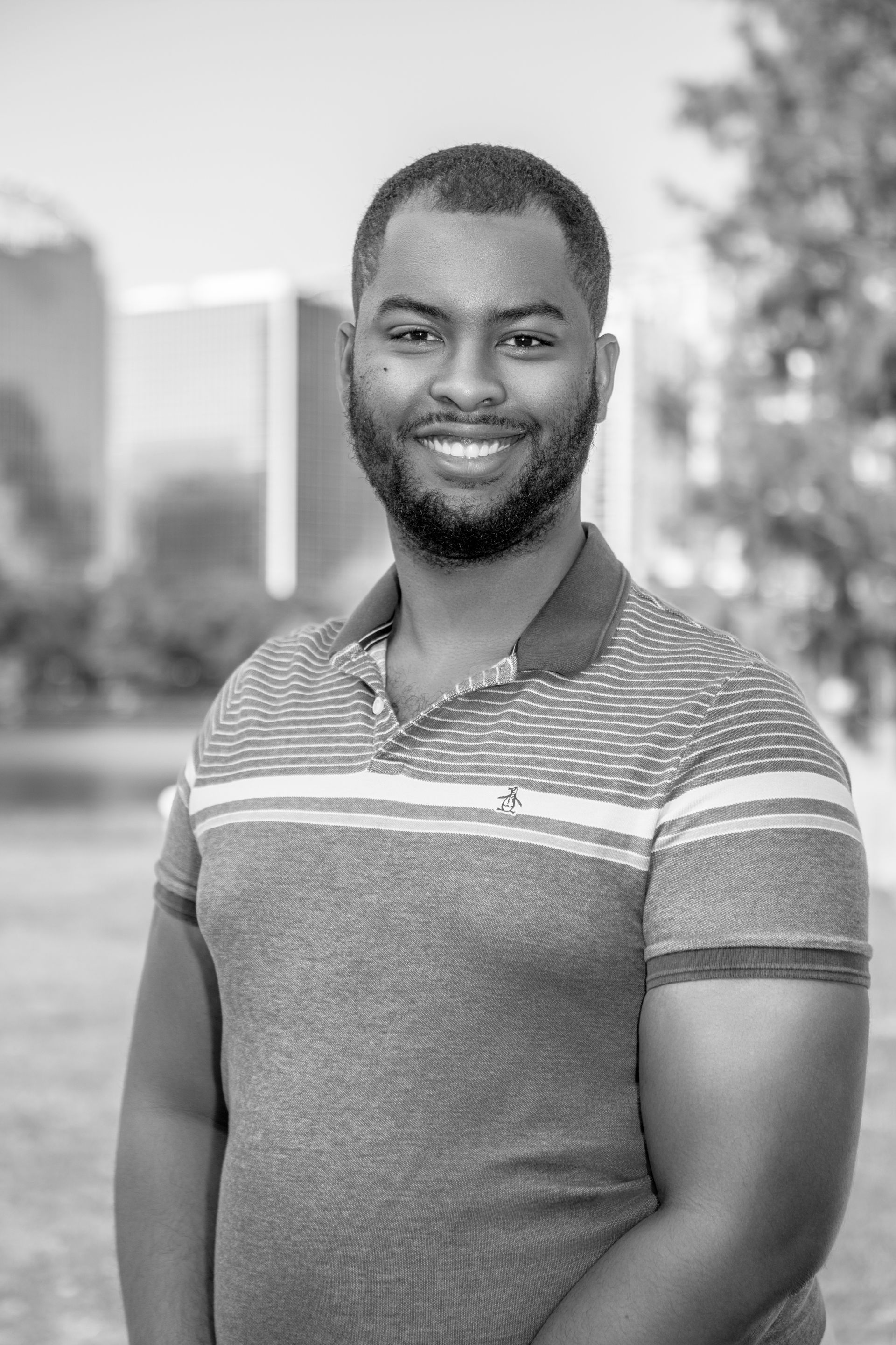 A black and white photo of a man with a beard wearing a polo shirt.