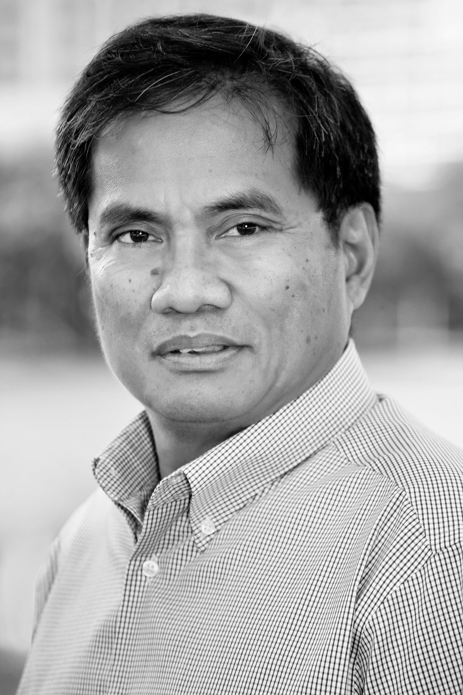 A man in a striped shirt is looking at the camera in a black and white photo.
