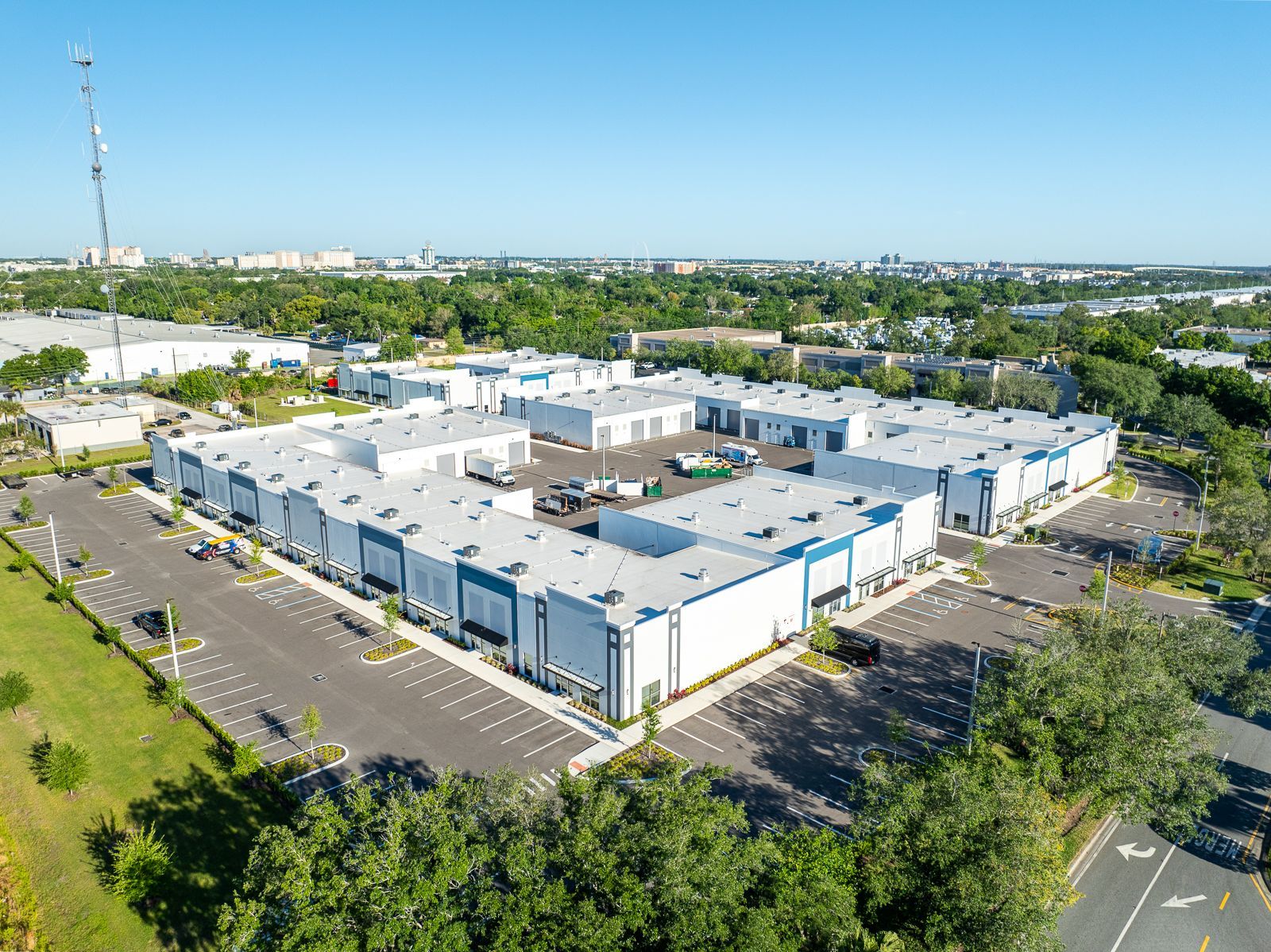 An aerial view of a large warehouse complex surrounded by trees and a parking lot.