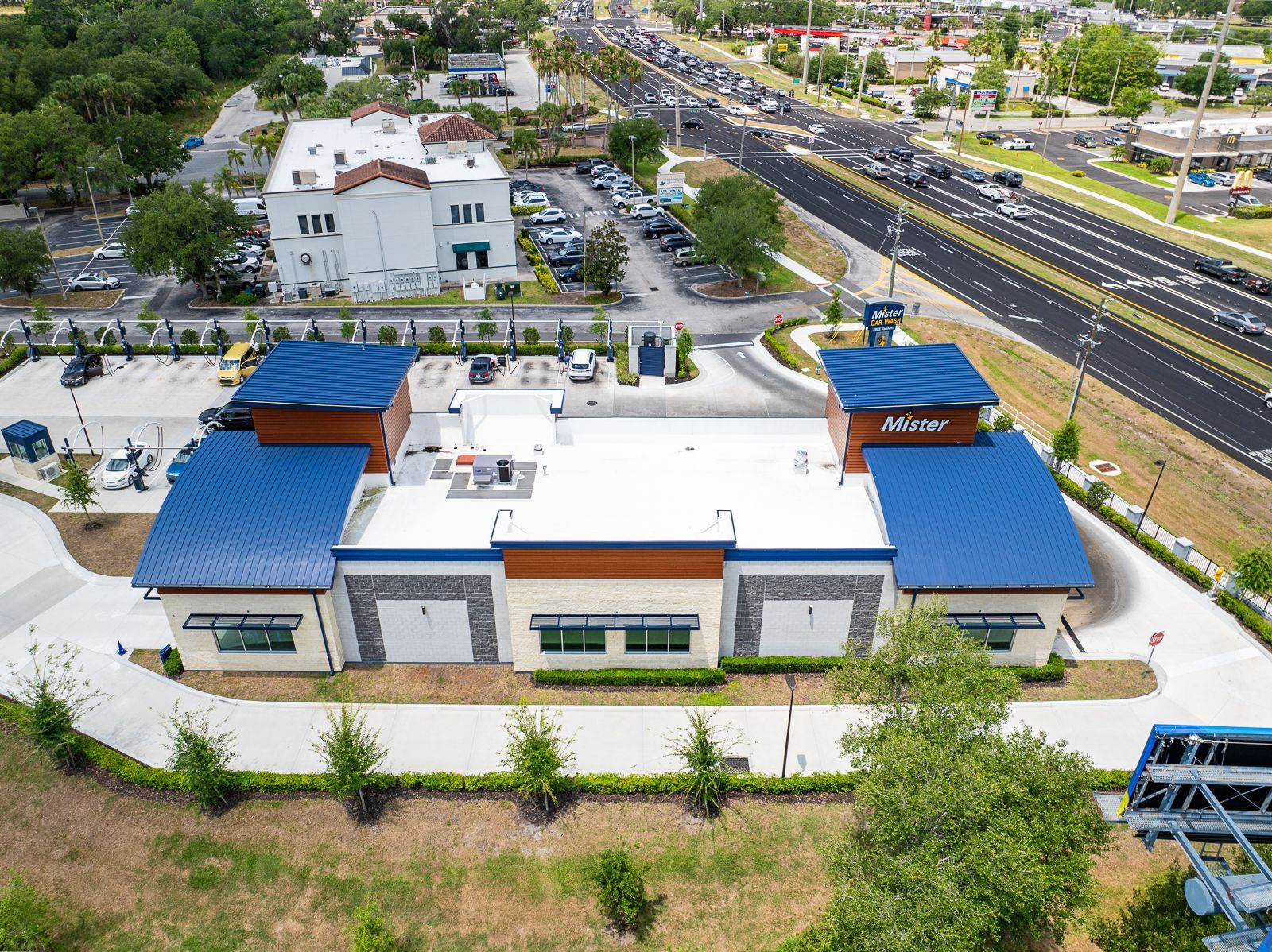 An aerial view of a building with a blue roof and a lot of cars parked in front of it.