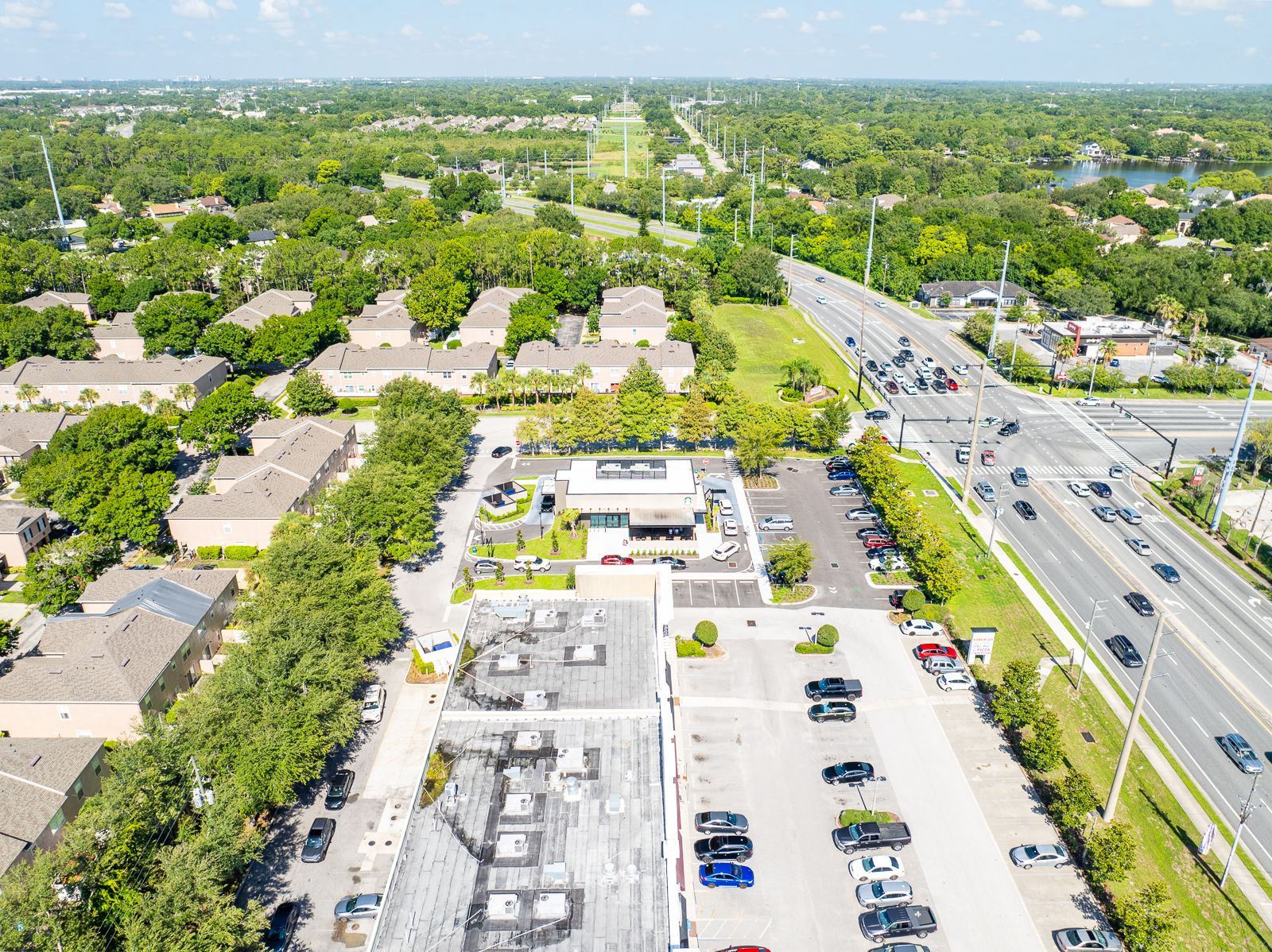 An aerial view of a residential area with a parking lot and a highway.
